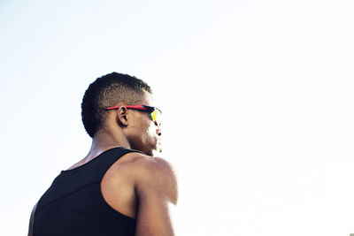 Low angle view of male athlete wearing sunglasses against clear sky