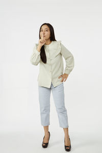 Portrait of young woman standing against white background