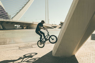 Man riding bmx cycle on footpath in city