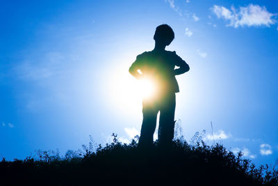 Low angle view of silhouette man standing against blue sky