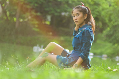 Side view of woman sitting on grass in field