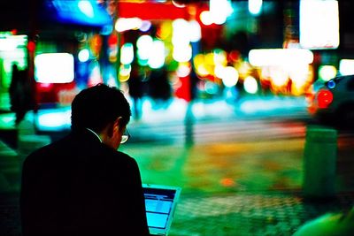 Woman in illuminated city at night