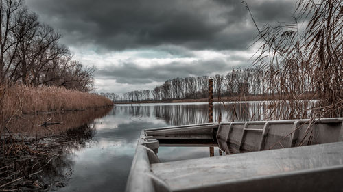 Reflection of bare trees in lake against sky