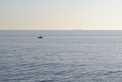 Boat sailing in calm sea against clear sky