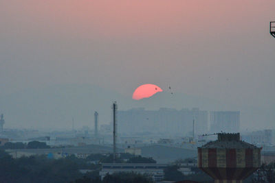 Hot air balloon in city against sky at sunset