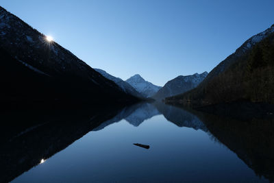 Scenic view of lake and mountains against clear blue sky