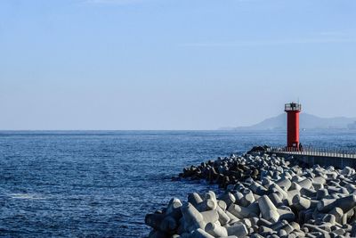 Lighthouse by sea against sky