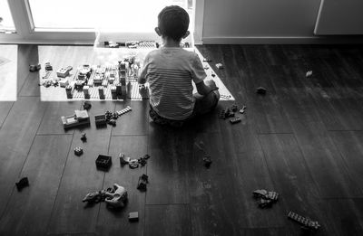 Little boy playing on the floor of a room in the house in front of a bay window