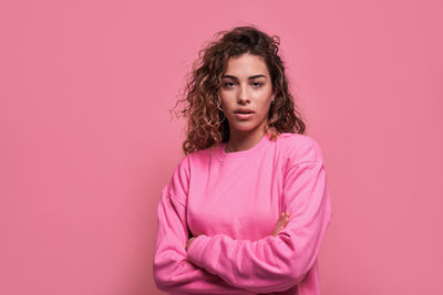 Portrait of beautiful young woman against pink background