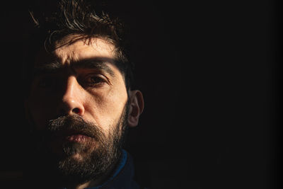 Man's face on black background behind a window with bars