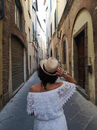 Rear view of woman standing on street amidst buildings