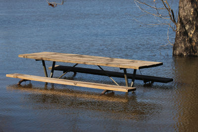 Rear view of woman sitting on bench by lake