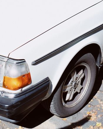 CLOSE-UP OF VINTAGE CAR ON ROAD AGAINST SKY