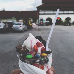 Hand holding ice cream in city