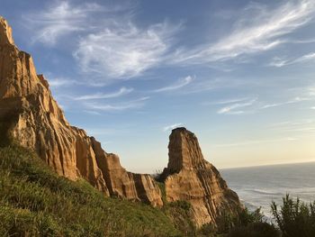 Rock formations by sea against sky