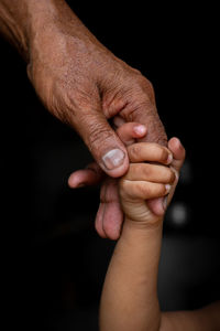 Close-up of hand holding hands over black background