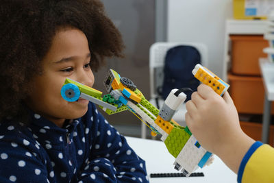Coding class, school girl constructing robot arm mechanism. multiethnic children making science