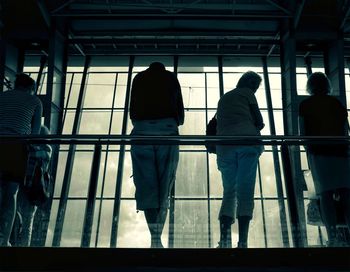 Rear view of people walking on glass window