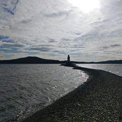 Silhouette people on shore by sea against sky
