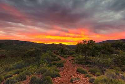 Scenic view of landscape against dramatic sky during sunset