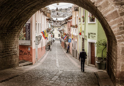 Rear view of people walking on footpath amidst buildings in city