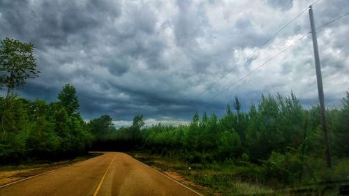 Empty road against cloudy sky