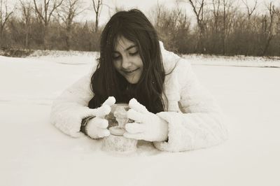 Smiling girl with decoration lying on snow covered field