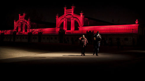 People standing by illuminated building at night