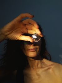 Close-up of woman holding diamond in front of face