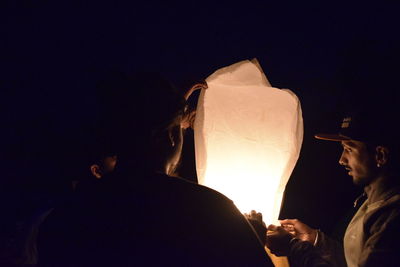 People standing against illuminated clear sky at night