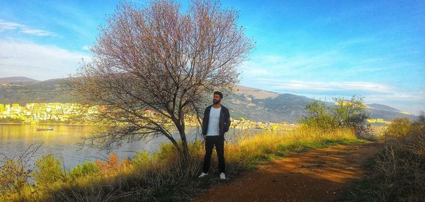 Man standing by tree against sky