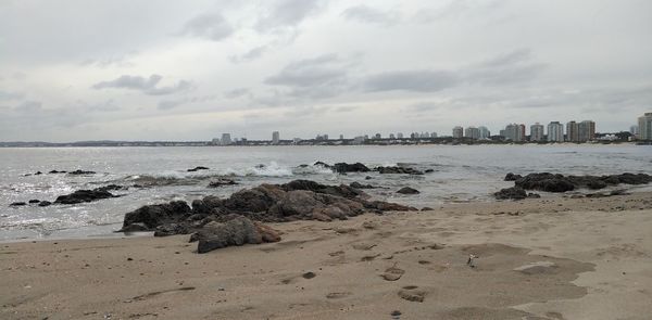 Rocks on beach against sky in city