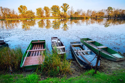 Abandoned boat moored at lakeshore against sky