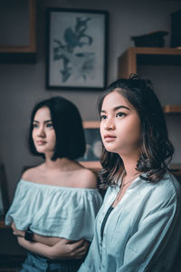 Two young women looking away at home