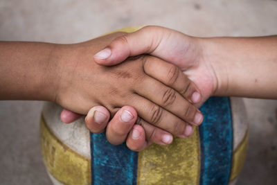 Close-up of children doing handshake over ball