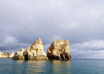 View of rock formation in sea against sky