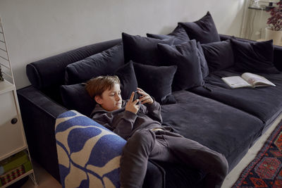 Boy lying on sofa and using cell phone