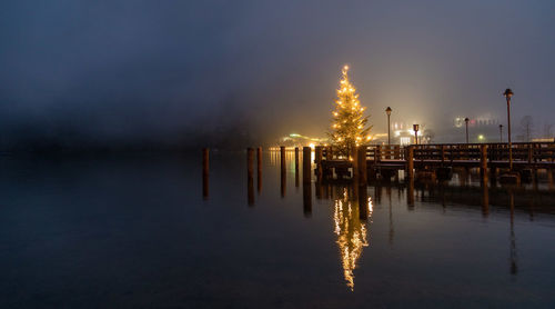 Wooden posts in sea against sky at night