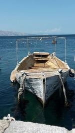 Old boat moored at lake against sky