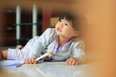 Portrait of cute baby girl sitting on table at home