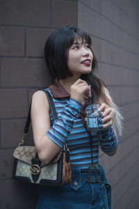 Portrait of young woman standing against wall