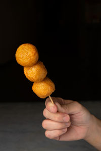 Close-up of hand holding lemon against black background