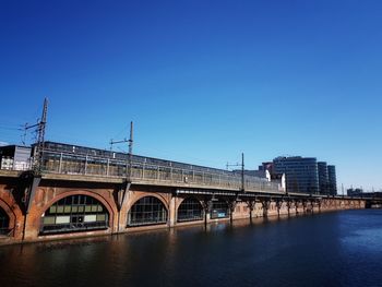 Arch bridge over river against clear blue sky