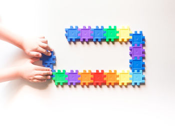 Close-up of baby hand against colored background