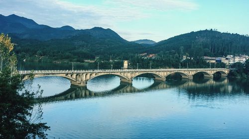 Arch bridge over river against sky