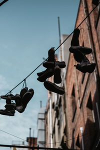 Low angle view of shoes hanging on street against sky