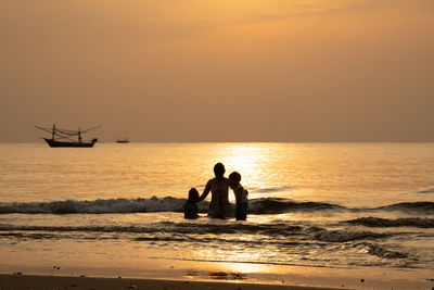 Silhouette people on beach against sky during sunset