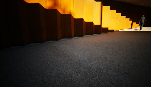 Rear view of man walking by orange wall