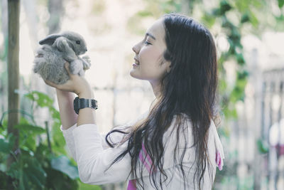 Smiling woman carrying rabbit outdoors