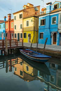 Boats moored in canal by buildings in city